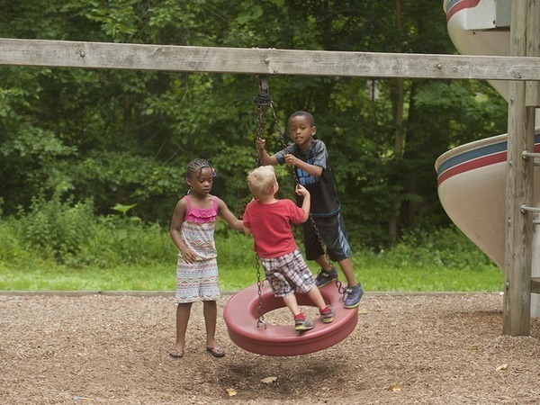 three children playing on a tire swing.