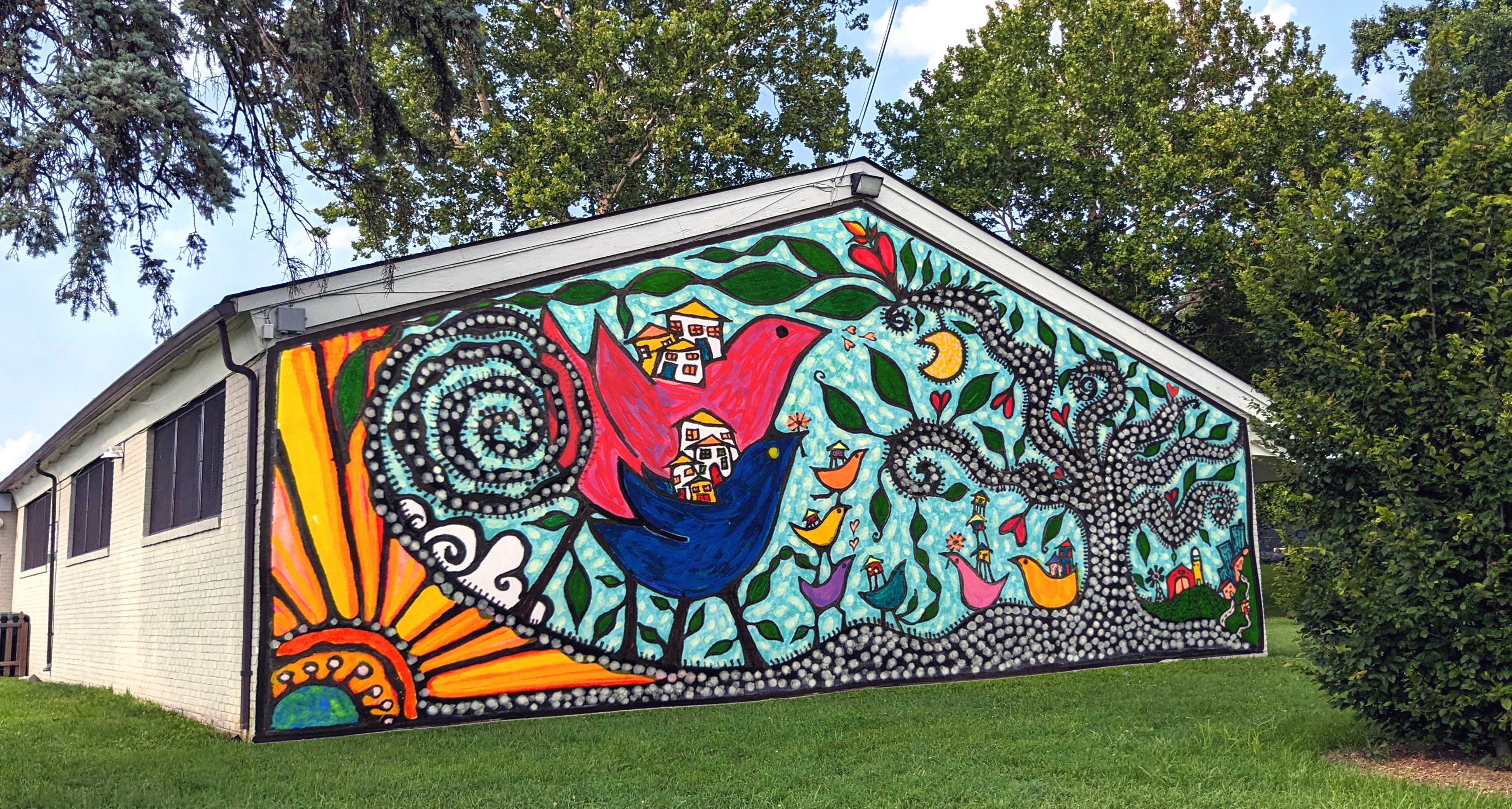 Mural design concept titled Paisaje Mágico/ Magical Landscape. The Image is a rendering of the front-facing wall with whimsical birds, houses, flowers, and trees